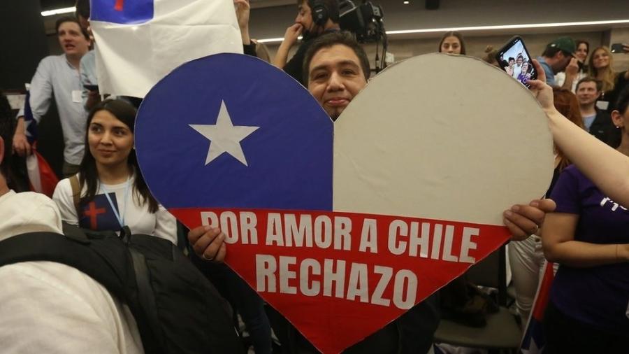 Homem com cartaz em forma de coração e as cores da bandeira do Chile onde se lê: "Por amo ao Chile, rejeito" - EPA