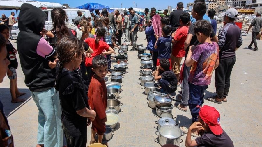 21.mai.2025 - Palestinos aguardam em fila para receber uma refeição em um ponto de distribuição na cidade de Gaza 21.mai.2025 - Palestinos aguardam em fila para receber uma refeição em um ponto de distribuição na cidade de Gaza