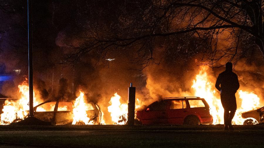 17.abr.2022 - Um manifestante ao lado de carros em chamas em Malmo durante protestos gerados por planos de um grupo de extrema-direita para queimar publicamente cópias do Alcorão  - Johan Nilsson/TT News Agency/AFP