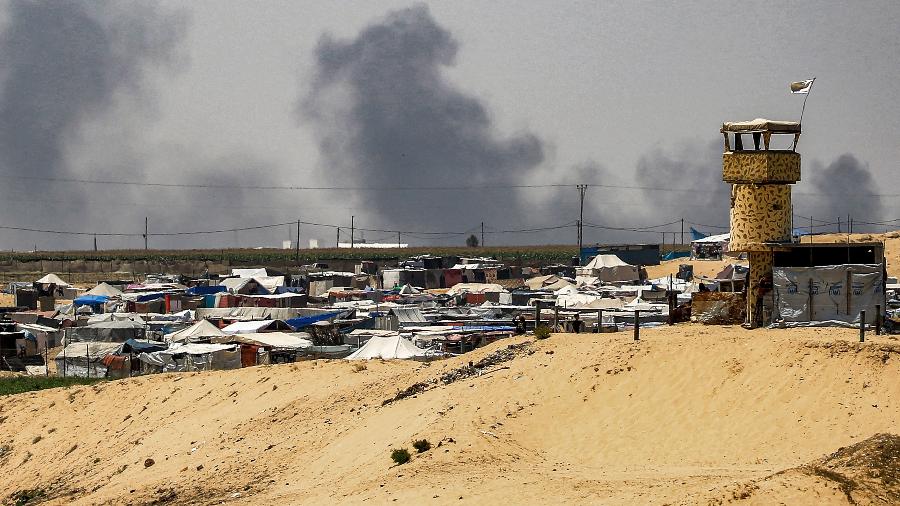 Nuvens de fumaça ondulam perto das tendas que abrigam palestinos deslocados em Rafah, no sul da Faixa de Gaza, em 4 de junho de 2024
