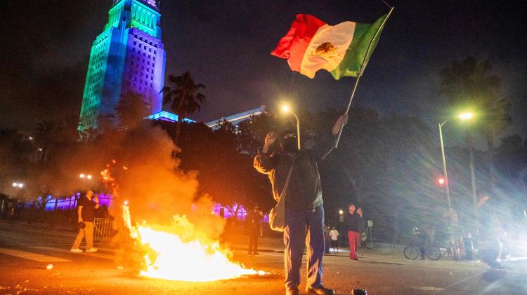 Manifestante com a bandeira do México enfrenta policiais federais em protesto contra a política de imigração de Trump em Los Angeles Manifestante com a bandeira do México enfrenta policiais federais em protesto contra a política de imigração de Trump em Los Angeles