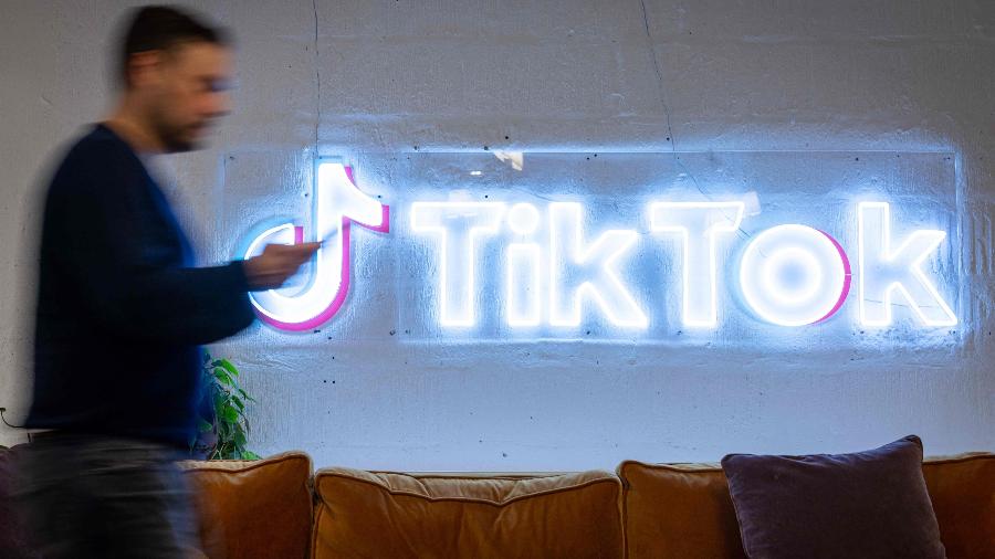 Funcionário caminha ao lado de logotipo do TikTok em escritório da empresa em Londres, no Reino Unido - Tolga Akmen/AFP