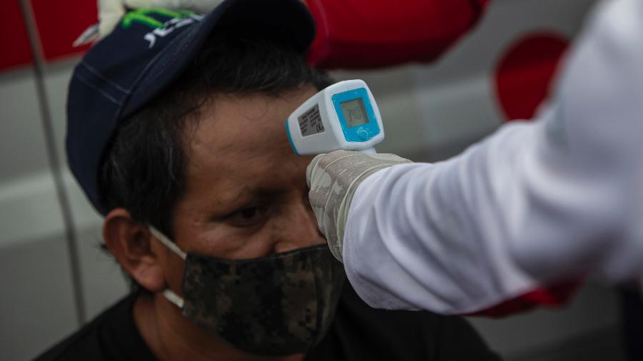 Voluntário da Cruz Vermelha mede temperatura de homem na Nicarágua - AFP