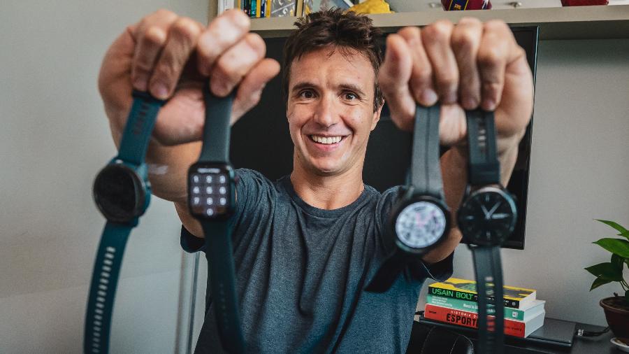 Médico Paulo Puccinelli segura quatro smartwatches; da esquerda para a direita: Xiaomi Mi Watch, Apple Watch SE, Galaxy Watch 5 e Huawei GT Runner
