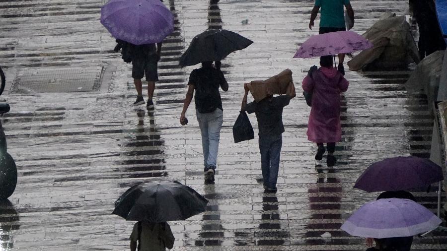 Pedestres se protegem da chuva na região central da cidade de São Paulo, no final da tarde desta terça-feira (18). Pedestres se protegem da chuva na região central da cidade de São Paulo, no final da tarde desta terça-feira (18).