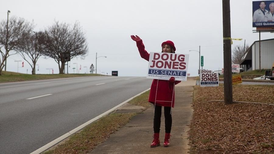 07.dez.2018 - LaNita Bennett acena para carros que passam, enquanto segura uma placa para o candidato democrata ao Senado Doug Jones em Anniston, Alabama - Maura Friedman/The New York Times