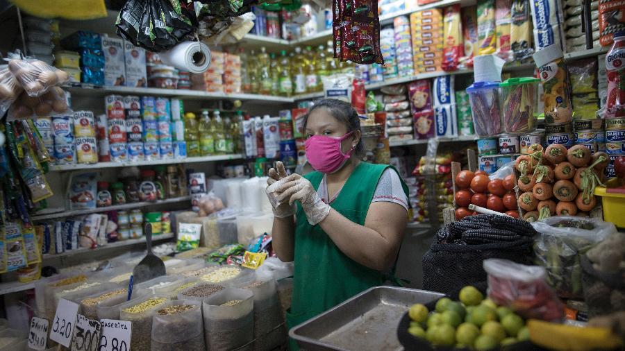 Mulher trabalha em comércio de Lima, no Peru, durante pandemia do coronavírus - Stringer/Getty Images