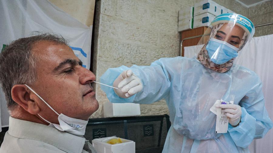 10.ago.2021 - Profissional de saúde realiza teste de covid-19 em homem em centro médico em Jerusalém - Hazem Bader/AFP