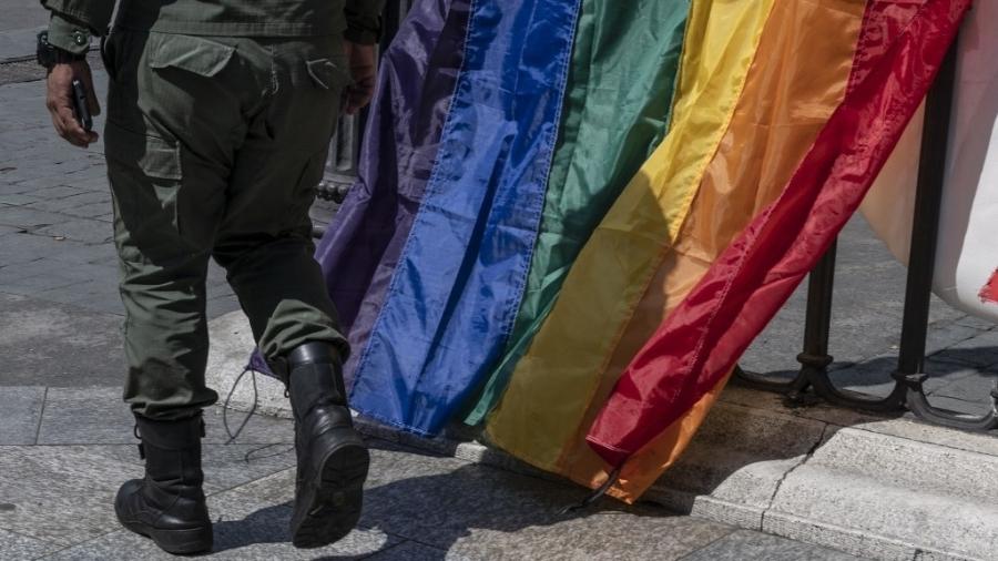 Membro da guarda nacional bolivariana caminha em frente a bandeiras do arco-íris de manifestação da comunidade LGBT em Caracas, na Venezuela