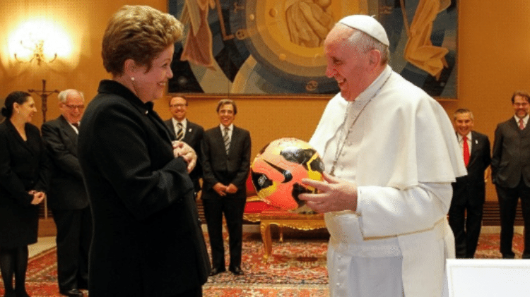 21.fev.2014 - O papa Francisco foi presenteado pela então presidente Dilma Rousseff com camisas da seleção brasileira, autografadas por Pelé, e uma bola de futebol. O pontífice, por sua vez, deu à chefe do Executivo brasileiro um terço. 21.fev.2014 - O papa Francisco foi presenteado pela então presidente Dilma Rousseff com camisas da seleção brasileira, autografadas por Pelé, e uma bola de futebol. O pontífice, por sua vez, deu à chefe do Executivo brasileiro um terço.