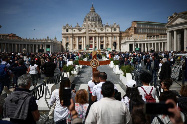 Um peregrino carrega uma cruz perto da Praça de São Pedro após a morte do Papa Francisco Um peregrino carrega uma cruz perto da Praça de São Pedro após a morte do Papa Francisco