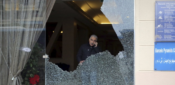 Investigador da polícia é visto através de vidro quebrado em hotel atacado por homens armados no Cairo, no Egito - Asmaa Waguih/Reuters