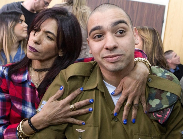 O soldado israelense Elor Azaria é abraçado pela mãe, Oshra, no começo de audiência judicial em Tel Aviv - Jim Hollander/AFP