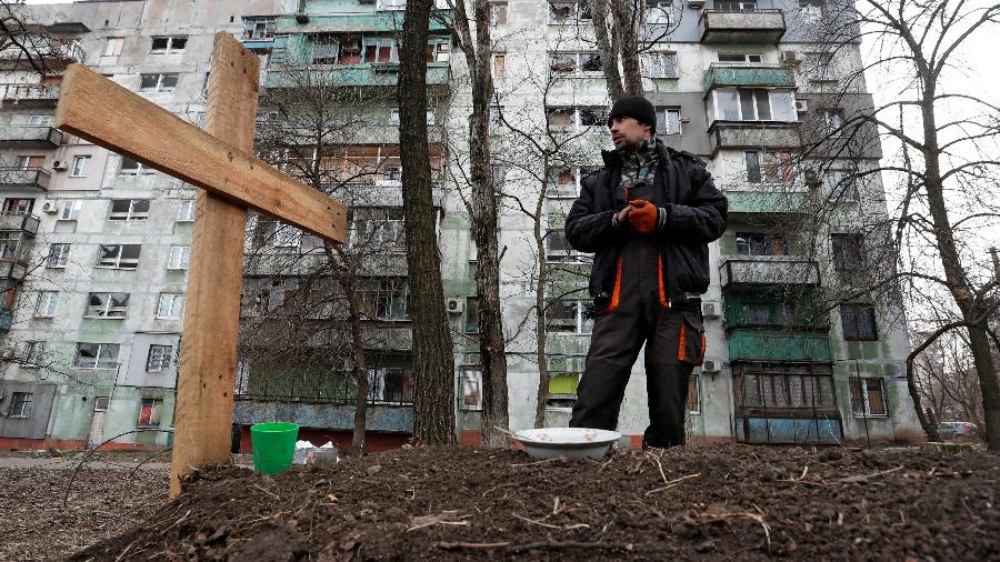 31.mar.2022 - Morador local fica ao lado do túmulo de seu amigo morto durante o conflito Ucrânia-Rússia em Mariupol - Reuters