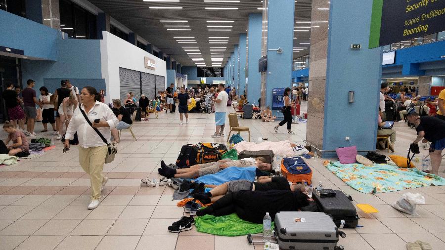 24.jul.23 - Turistas dormem enquanto esperam a partida de aviões no aeroporto, após serem evacuados após um incêndio florestal na ilha de Rodes, na Grécia