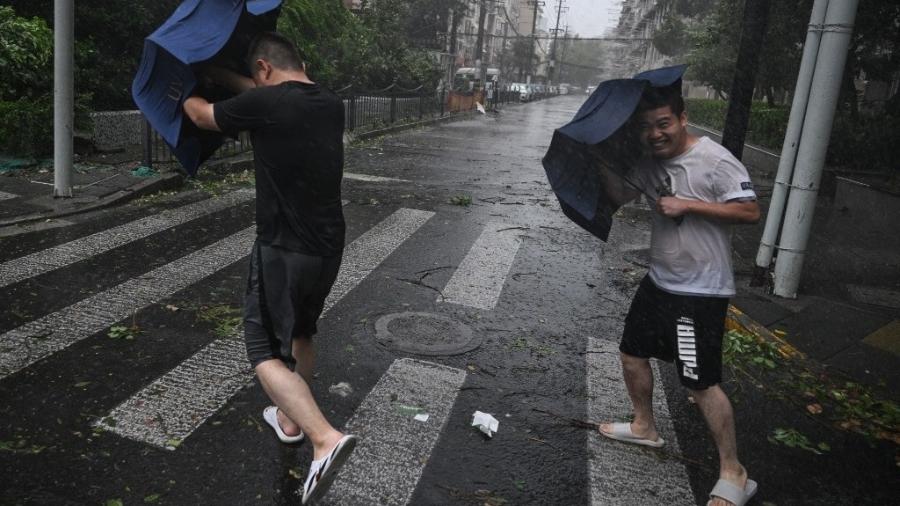 Pedestres lutam com seus guarda-chuvas em ventos fortes e chuva da passagem do Tufão Bebinca em Xangai em 16 de setembro de 2024