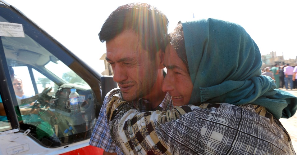 4.set.2015 - Abdullah Kurdi chora ao lado de parente durante funeral de seus filhos e sua mulher, em Kobani, na Síria