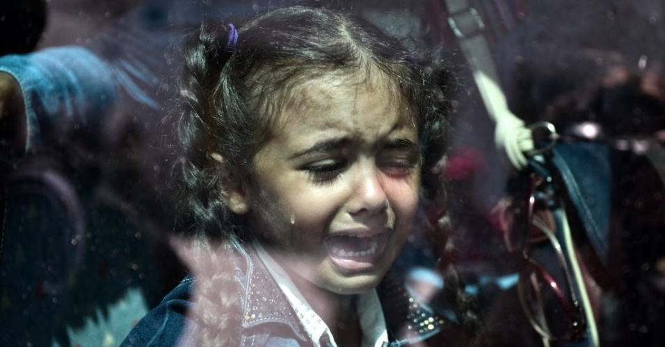 8.set.2015 - Criança chora dentro de ônibus superlotado que transporta refugiados para estações de metrô e trem, depois de terem desembarcado de uma balsa fretada pelo governo no porto de Piraeus, na região de Atenas, na Grécia