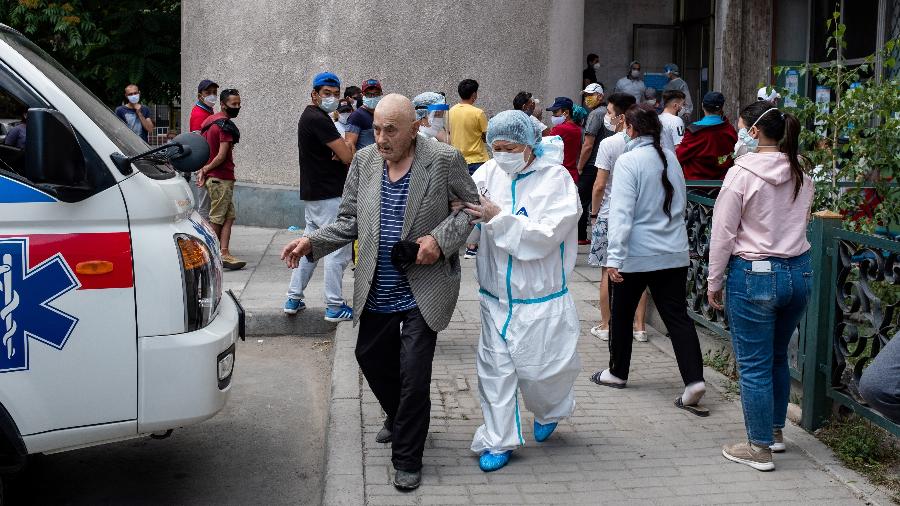 Médico ajuda um idoso rumo à uma ambulândia em frente a um centro médico para coronavírus em Bishkek - DANIL USMANOV / AFP