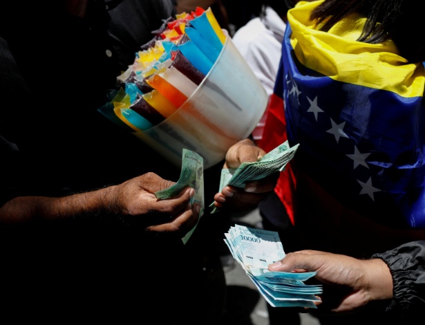 Vendedor de geladinho conta maço de notas de bolívares venezuelanos em Caracas - Marco Bello/Reuters