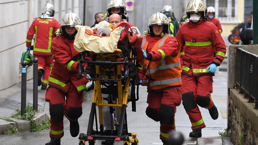 25.set.2020 - Bombeiros socorrem ferido após Ataque a faca perto da antiga sede do jornal Charlie Hebdo, em Paris - Alain Jocard/AFP