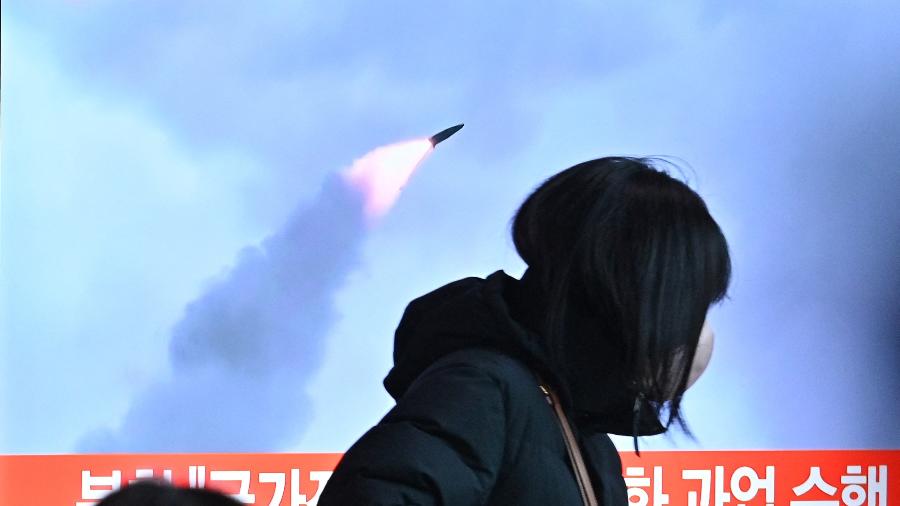 11.jan.2022 - Pessoas passam por uma tela de televisão mostrando noticiário com imagens de arquivo de um teste de míssil norte-coreano, em uma estação ferroviária em Seul  - Anthony Wallace/AFP