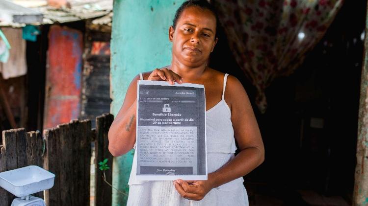 Moradora da favela Mundaú, em Maceió, mostra corte feito pelo governo a seu auxílio Imagem: Gabriel Moreira/UOL