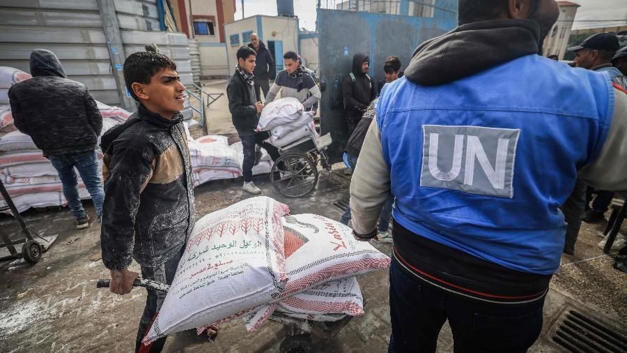 Palestinos desalojados recebem comida da UNRWA, agência da ONU, em Rafah, no sul da Faixa de Gaza