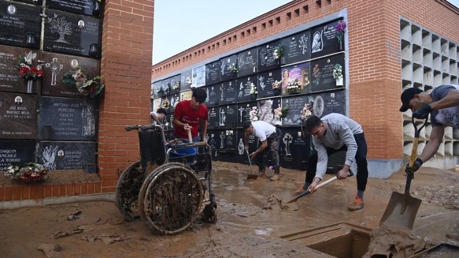 Esta foto tirada em 1º de novembro de 2024 mostra um grupo de pessoas limpando lama em um cemitério após uma inundação devastadora na cidade de Alfafar, na região de Valência, leste da Espanha