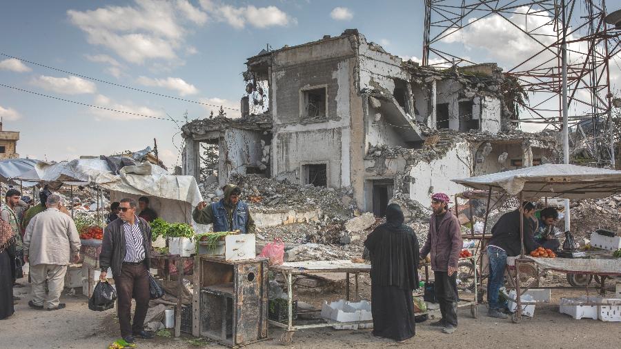 Camelôs vendem frutas e vegetais perto de ruínas em praça na cidade de Raqqa, na Síria - Ivor Prickett/The New York Times