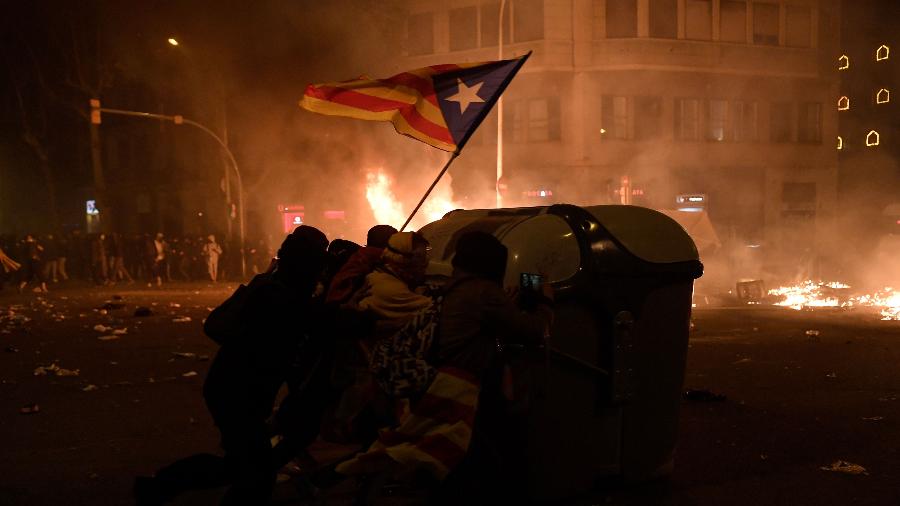 18.oct.2019 - Manifestantes se protegem de confrontos em Barcelona - Josep Lago / AFP