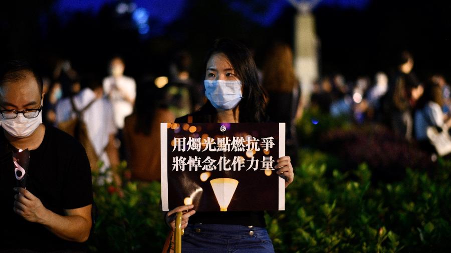 Ativista segura um cartaz durante uma lembrança à luz de velas do lado de fora do Victoria Park, em Hong Kong - Anthony WALLACE / AFP