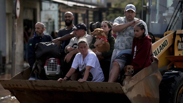 Pessoas são transportadas em retroescavadeira após serem resgatadas no bairro Sarandi, em Porto Alegre