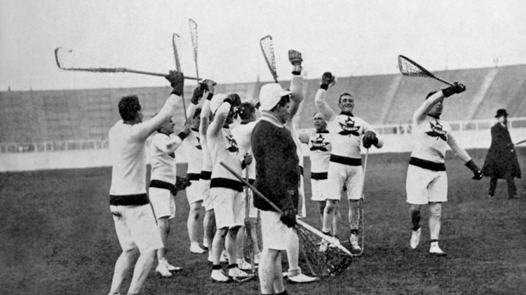 Time do Canadá comemorando o título de campeão do lacrosse em jogo contra a Grã Bretanha nas Olimpíadas de 1908, na Inglaterra. Na modalidade, jogadores tentam arremessar uma bola de borracha no gol adversário usando um taco com uma rede na ponta