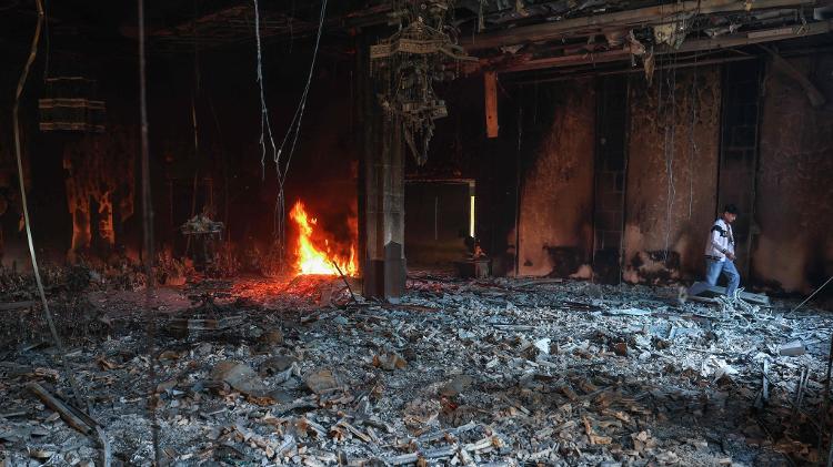 Jovem passa por um incêndio em uma sala do palácio residencial Tishrin