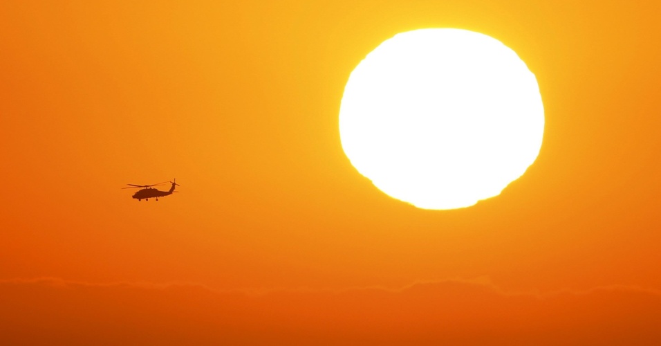 25.jun.2015 - Um helicóptero voa sobre o oceano Pacífico passando pelo sol perto de Cardiff, na Califórnia (EUA)