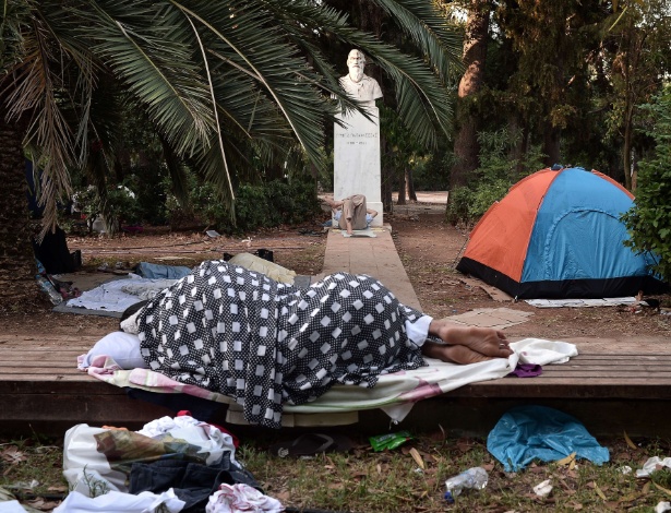 Imigrantes dormem ao ar livre no centro de Atenas, em local de abrigo temporário - Louisa Gouliamaki/AFP