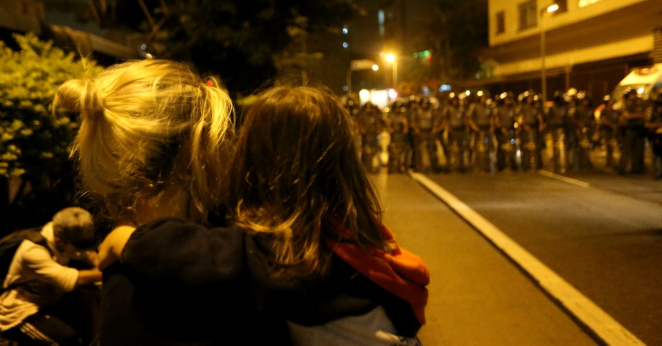 1º.dez.2015 - Com criança no colo, mulher observa a polícia se aproximar de protesto de estudantes que bloqueava a avenida Nove de Julho, em São Paulo (SP), antes de confronto