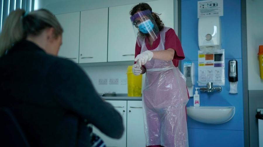 16.abr.2020 - De avental e proteção no rosto, enfermeira atende paciente em Altrincham, no Reino Unido - Christopher Furlong/Getty Images