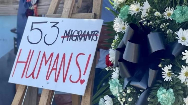 A poster placed at the location of the truck reads '53 people', with the word 'immigrants' crossed out.