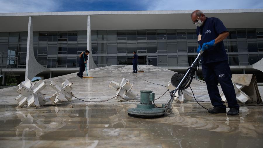 Trabalhadores limpam o piso do Palácio do Planalto após ataques - MAURO PIMENTEL / AFP