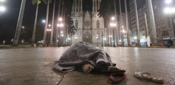 Morador de rua se abriga do frio enquanto dorme durante a madrugada frente da Cadetral da Sé, no centro de São Paulo - Alex Silva/Estadão Conteúdo
