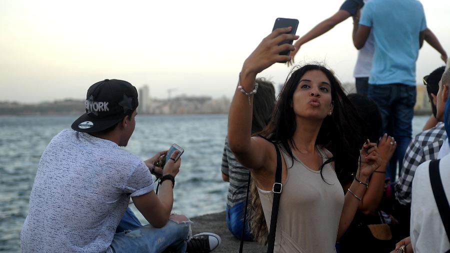 Jovem cubana faz uma selfie no Malecón, em Havana. Os cubanos de vinte e trinta anos estão determinados a modernizar e globalizar o país - Yamil Lage/Agência France-Presse/Getty Images