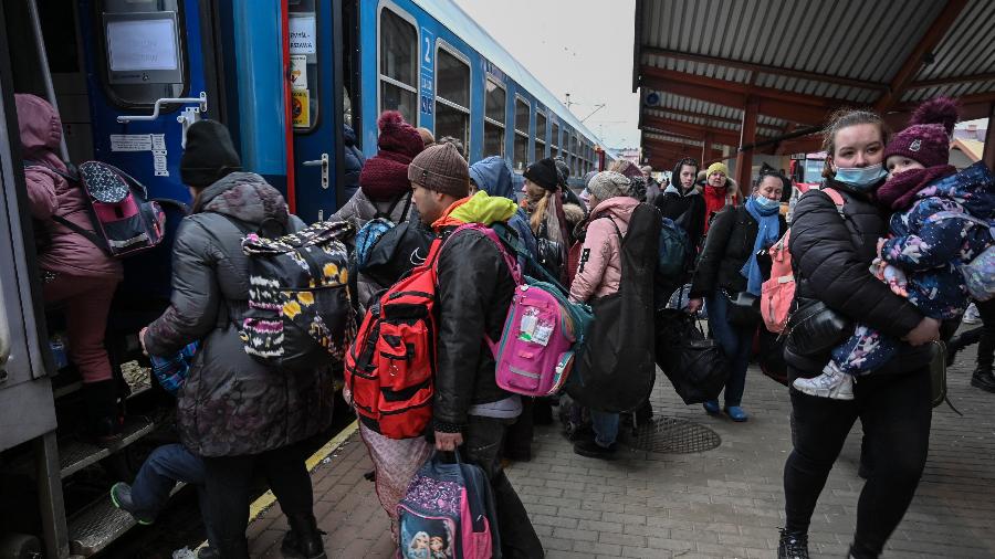 Refugiados da Ucrânia embarcam no trem para Varsóvia, na estação ferroviária de Przemysl, perto da fronteira polaco-ucraniana - Louisa Gouliamaki/AFP