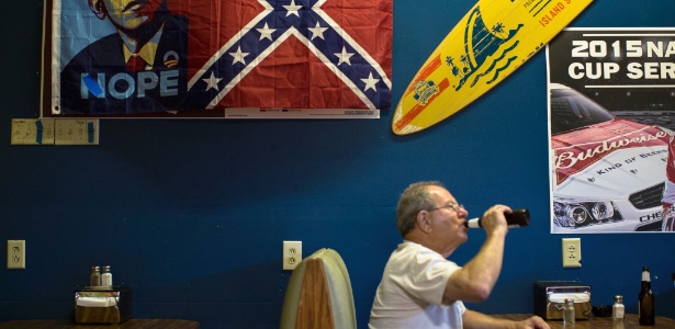 Bob Murray bebe uma cerveja abaixo de uma bandeira confederada com arte da campanha presidencial de Barack Obama em 2008, no Georgia Peach Oyster Bar - Kevin Liles/The New York Times