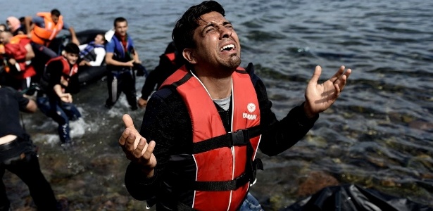 Homem ora após pisar em terra firme na ilha grega de Lesbos, depois de atravessar o Mediterrâneo