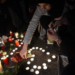 Mulher coloca flor em homenagem ao garoto que desapareceu de centro de refugiados em Berlim