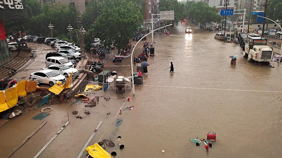 Pessoas atravessam rua inundada em meio a fortes chuvas em Zhengzhou, província de Henan, na China; 50 pessoas continuam desaparecidas - REUTERS