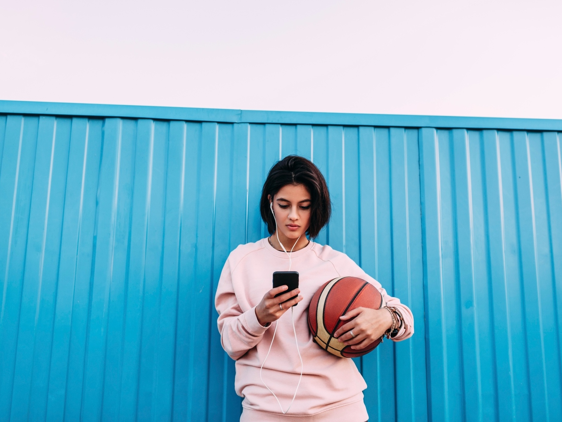 Esportivo com bola para jogar basquete, ouvindo música em fones