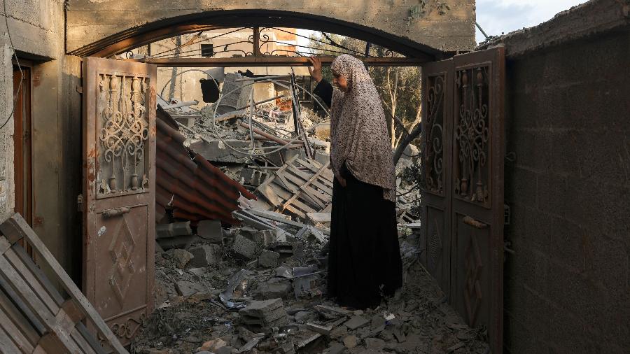 Mulher nos escombros da casa dela após ataque de Israel ao sul da faixa de Gaza